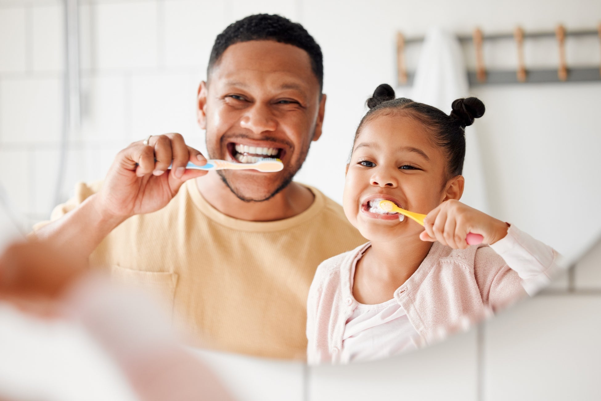 Child, dad and brushing teeth in a family home bathroom for dental health and wellness in a mirror by K.A.