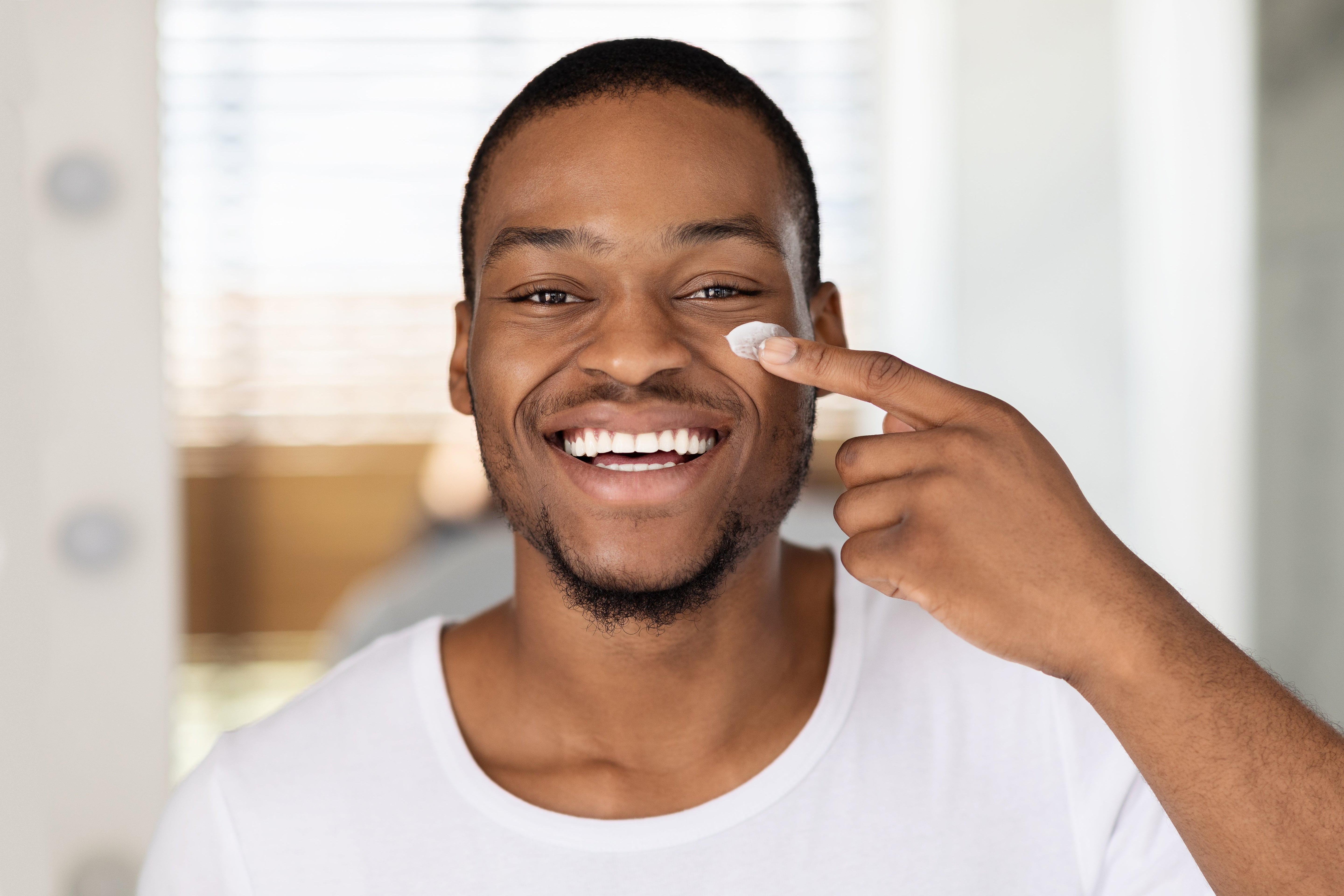 Man applies a facial cleanser while cleaning his face by Prostock-studio